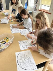 Photograph shows multiple children at the Coddington Road Community Center coloring their brain coloring pages. 
