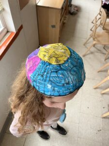 Photograph of a child showing off their colored brain hat.